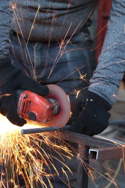 Angle grinder cutting rebar, sparks flying. Angle grinder with metal disc and no casing, safety violation. Close-up of gloved hands with grinder. Repair work. Close-up of construction work in progress