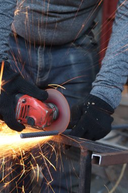 Angle grinder cutting rebar, sparks flying. Angle grinder with metal disc and no casing, safety violation. Close-up of gloved hands with grinder. Repair work. Close-up of construction work in progress