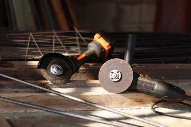 İki açılı öğütücü yakın plan. Kablosuz ve kablosuz açı öğütücüler, inşaat ve onarım için elektrikli aletler. Aletler yakın plan. Ülkedeki tamirat işleri. Metal diskleri olan öğütücüler.