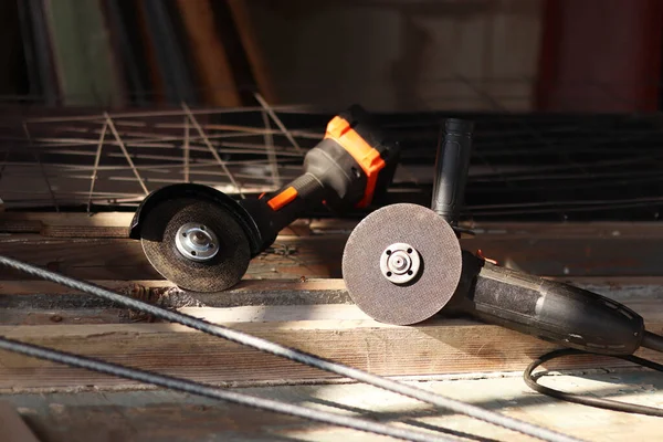 İki açılı öğütücü yakın plan. Kablosuz ve kablosuz açı öğütücüler, inşaat ve onarım için elektrikli aletler. Aletler yakın plan. Ülkedeki tamirat işleri. Metal diskleri olan öğütücüler.