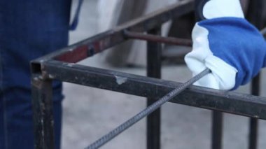 Close-up of an angle grinder cutting rebar. Female hands in work gloves holding a cordless grinder and cutting rebar into small pieces. Power tool for construction and repair work