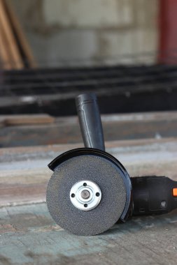 Metal kesici diskli kablosuz öğütücü, yakın plan. Kulübede ya da inşaatta tamirat. Kablosuz kablosuz öğütücü. Elektrikli aletler, inşaat malzemeleri