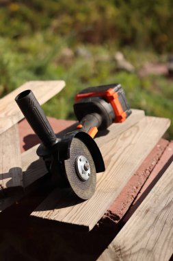 Metal kesici diskli kablosuz öğütücü, yakın plan. Kulübede ya da inşaatta tamirat. Kablosuz kablosuz öğütücü. Elektrikli aletler, inşaat malzemeleri