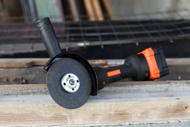 Metal kesici diskli kablosuz öğütücü, yakın plan. Kulübede ya da inşaatta tamirat. Kablosuz kablosuz öğütücü. Elektrikli aletler, inşaat malzemeleri