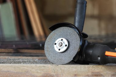 Metal kesici diskli kablosuz öğütücü, yakın plan. Kulübede ya da inşaatta tamirat. Kablosuz kablosuz öğütücü. Elektrikli aletler, inşaat malzemeleri