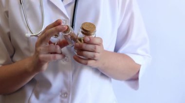 Medicines in the hands of a nurse or doctor. Tablets, capsules in glass jars in the hands of a pharmacist. Close-up of hands with medicines or dietary supplements. Doctor in a white coat