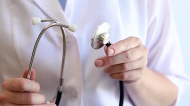 Close-up of a doctor's hands holding a stethoscope. Concept of medicine and health. Cardiologist in a white coat with a stethoscope in his hands. Doctor, nurse or intern. Medical instrument