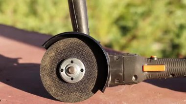 Cordless grinder on the veranda of the house. Power tool close-up. Cordless angle grinder with a disc for cutting metal. Repair and construction concept. Tool with a rechargeable battery
