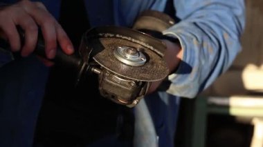 Kadın ellerinin kablosuz açı öğütücüsünü iş için hazırladığı yakın plan. Kadının elinde inşaat ve onarım için elektrikli alet var. Metre diski olan kablosuz açı öğütücüsü olan bir kadın. Kadın işçi.