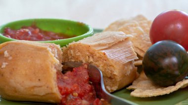 Yeşil plaka ve tomatillos yan görünüm üzerinde tatlı mısır tortilla ve domates sosu ile servis çatal kesme unwrapped tamale closeup - Meksika Gıda kavramı
