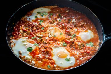 Lezzetli ve sağlıklı Shakshuka, yumurta baharatlı domates biber sosu içinde, bir kızartma tava, siyah arka planda Poached