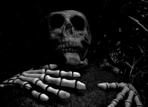 人が黒と白の大きな岩に不気味なハロウィーンの装飾によって殺されたことを示唆する頭蓋骨とスケルトンの手 — ストック写真