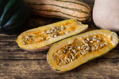 Üç çeşit kış kabağı, Delicata Kabağı, meşe palamudu ve tereyağı kabağı, narin kabak ikiye bölünmüş, bir açıdan bakıldığında, ahşap masa üzerinde.