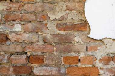 Eski bir tuğla duvarın düzensiz, dağınık tuğla işleri, alçı izleri ile.