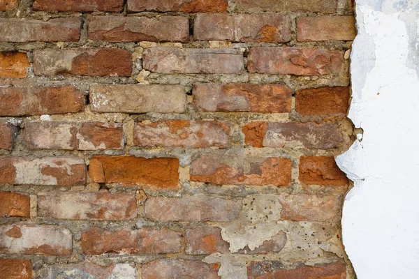 Eski bir tuğla duvarın düzensiz, dağınık tuğla işleri, alçı izleri ile.