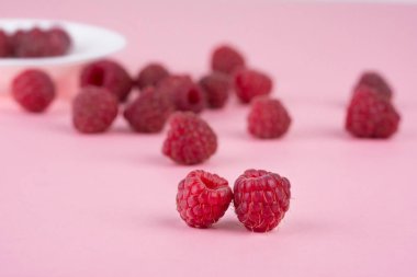 Taze olgun ahududu bir pembe arka plan dağınık. Yakın çekim, minimal şık gıda kavramı