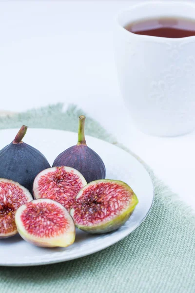 Taze incir. Vejetaryen yiyecekler. Beyaz arka plan üzerinde beyaz bir plaka üzerinde tüm ve dilimlenmiş incir. Uzay kopyalayın. Kavram kahvaltı.