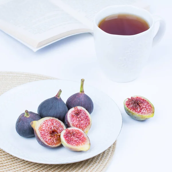 Taze incir. Vejetaryen yiyecekler. Beyaz arka plan üzerinde beyaz bir plaka üzerinde tüm ve dilimlenmiş incir. Uzay kopyalayın. Kavram kahvaltı.