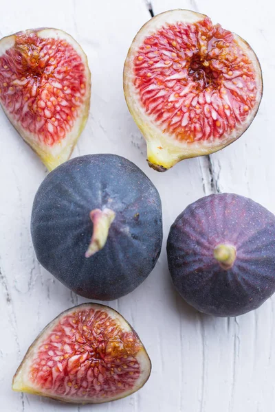 Taze incir. Vejetaryen yiyecekler. Beyaz ahşap zemin üzerinde tüm ve dilimlenmiş incir. Kopya alanı.