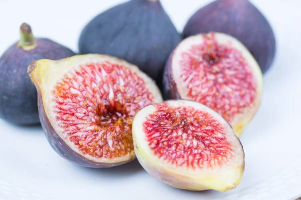 Taze incir. Vejetaryen yiyecekler. Beyaz arka plan üzerinde beyaz bir plaka üzerinde tüm ve dilimlenmiş incir. Uzay kopyalayın. Yakın çekim.