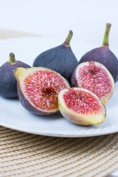 Taze incir. Vejetaryen yiyecekler. Beyaz arka plan üzerinde beyaz bir plaka üzerinde tüm ve dilimlenmiş incir. Uzay kopyalayın. Yakın çekim.