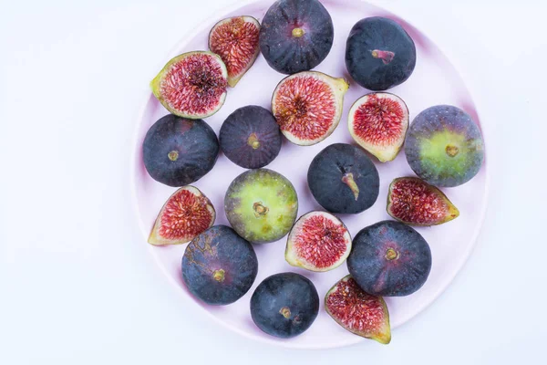 Taze incir. Vejetaryen yiyecekler. Beyaz arka plan üzerinde pembe bir plaka üzerinde tüm ve dilimlenmiş incir. Uzay kopyalayın. Kavram kahvaltı. Üstten görünüm.