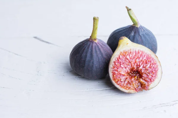 Taze incir. Vejetaryen yiyecekler. Beyaz ahşap zemin üzerinde tüm ve dilimlenmiş incir. Uzay kopyalayın. Yakın çekim.