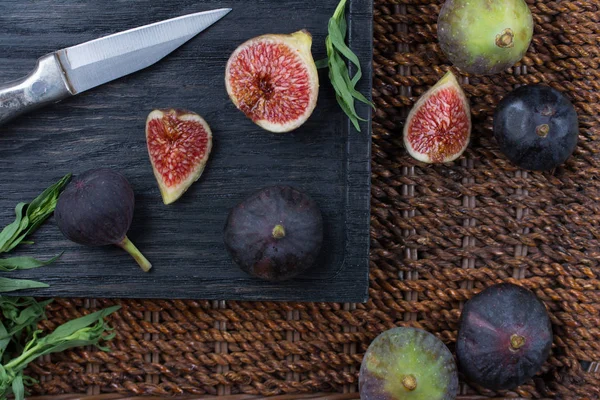 Taze incir. Vejetaryen yiyecekler. Bütün ve dilimlenmiş incir koyu ahşap arka plan üzerinde. Üstten görünüm. Yakın çekim.
