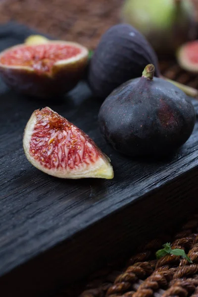 Taze incir. Vejetaryen yiyecekler. Bütün ve dilimlenmiş incir koyu ahşap arka plan üzerinde. Uzay kopyalayın. Yakın çekim.