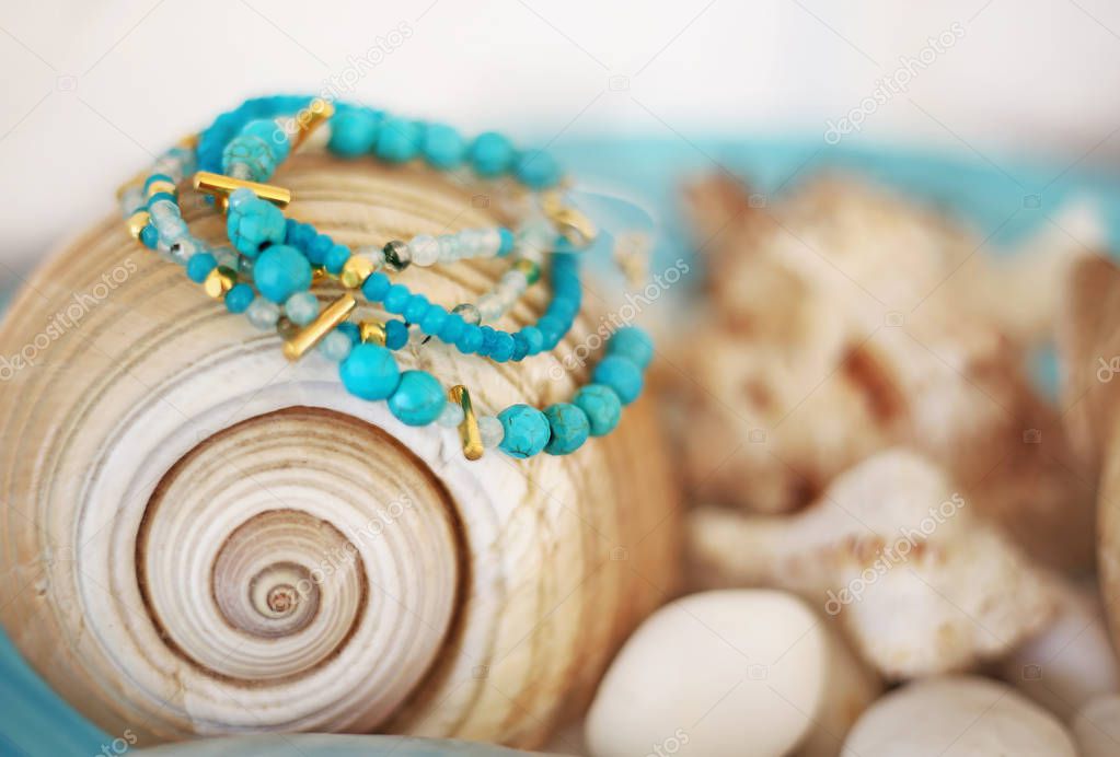 turquoise semi precious stones bracelets advertisement - blurry background with shells