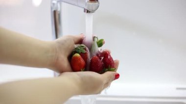 Kadın el ele tutuşup taze çilek yıkıyor. Ağır çekim su.
