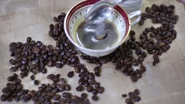 新鮮なエスプレッソコーヒーのカップに砂糖を追加 コーヒー粒の背景 — ストック動画