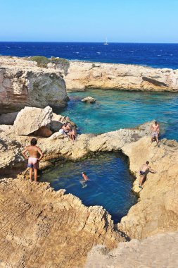 Ano Koufonisi Yunanistan, 27 Ağustos 2019: Yunanistan Ano Koufonisi Adası 'ndaki kayaların arasındaki deniz doğal havuzunda yüzen insanlar. Düzenleyici kullanımı.