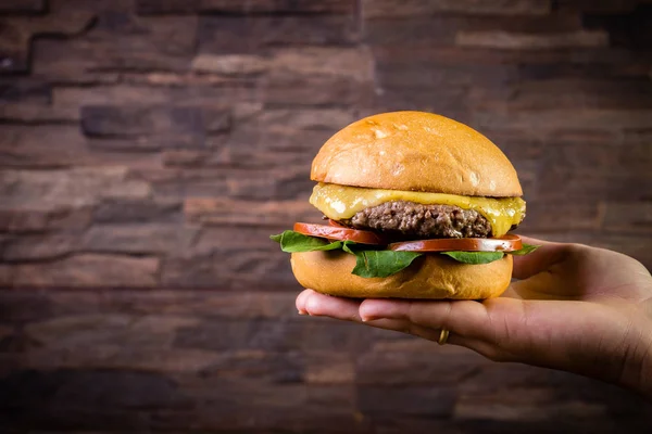 Mano sosteniendo una hamburguesa artesanal de carne —  Fotos de Stock