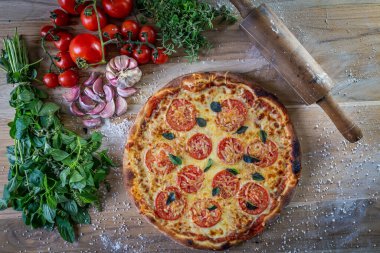 Mozzarella pizza ve yemek malzemeleri: domates, fesleğen, ahşap masa zemininde sarımsak.