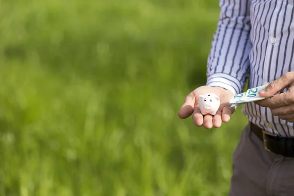 cropped image of man holding little piggy bank and cash