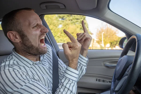 aggressive man driving car and gesturing middle fingers