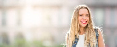 Mutlu genç kadın uzun saçlı açık havada gülüyor