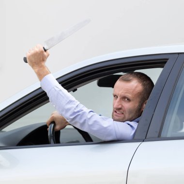 Agresif ve saldırgan sürücü büyük mutfak bıçağıyla silahlı. Kopya alanı gri arka plan üzerinde.