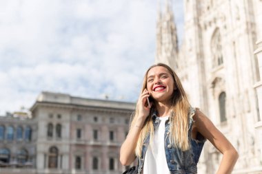 Güzel ve mutlu sarışın genç onu cep telefonu konuşurken açık. Milan, İtalya'da çekilmiş fotoğrafı.