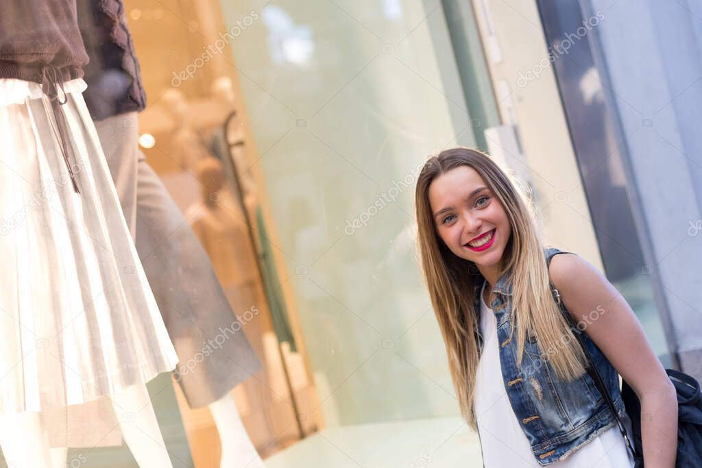 Pretty girl watching a fashion shop window. Fashion, lifestyle and retail concepts.