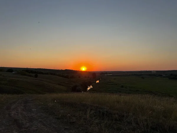Altın saat güneş ışığı, yuvarlanan tepelerin manzarasını ve günbatımında sakin bir nehri yıkıyor.