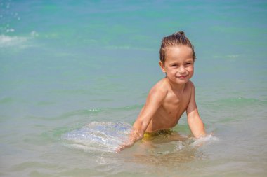 Mutlu küçük çocuk denizde oynuyor