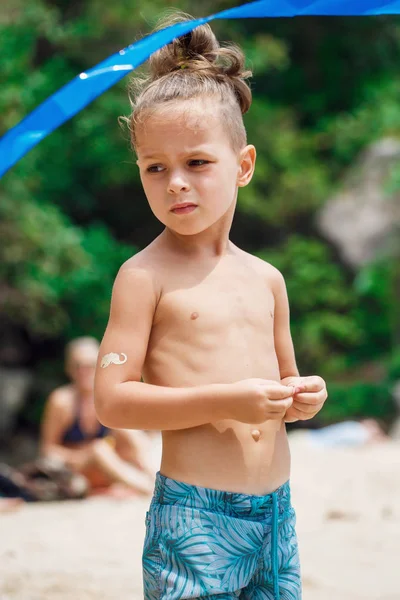 Petit garçon sérieux debout sur la plage — Photo
