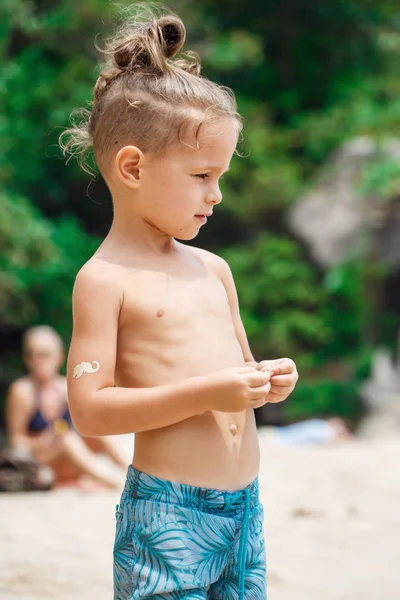 Petit garçon sérieux debout sur la plage — Photo