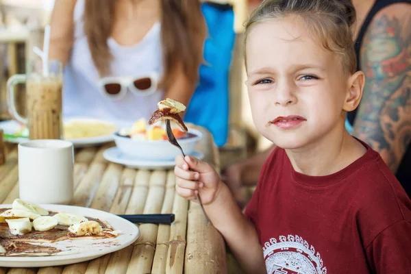 Boy eating pancake with banana and chocolate — Stock Photo, Image