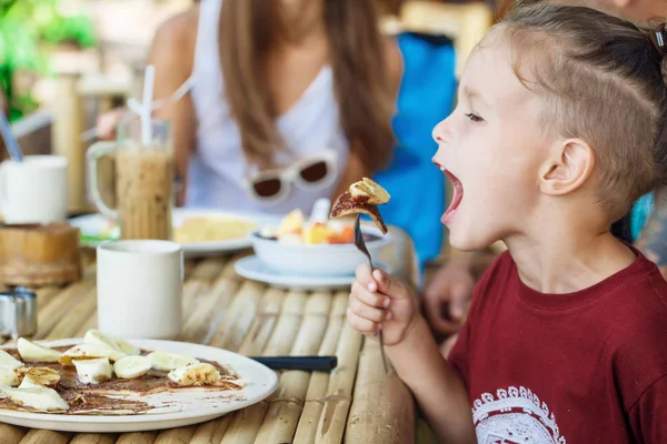 Boy eating pancake with banana and chocolate — Stock Photo, Image