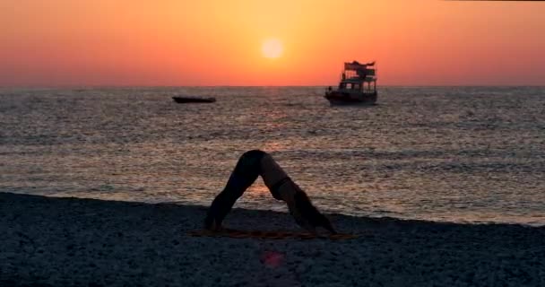 Young woman in bodysuit practicing yoga on the beach above. — Stock Video