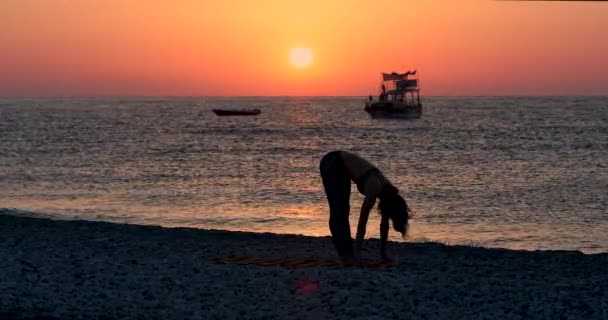 Giovane donna in body praticare yoga sulla spiaggia sopra . — Video Stock