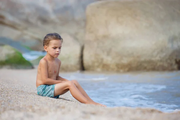 Menino sentado na areia junto ao mar — Fotografia de Stock